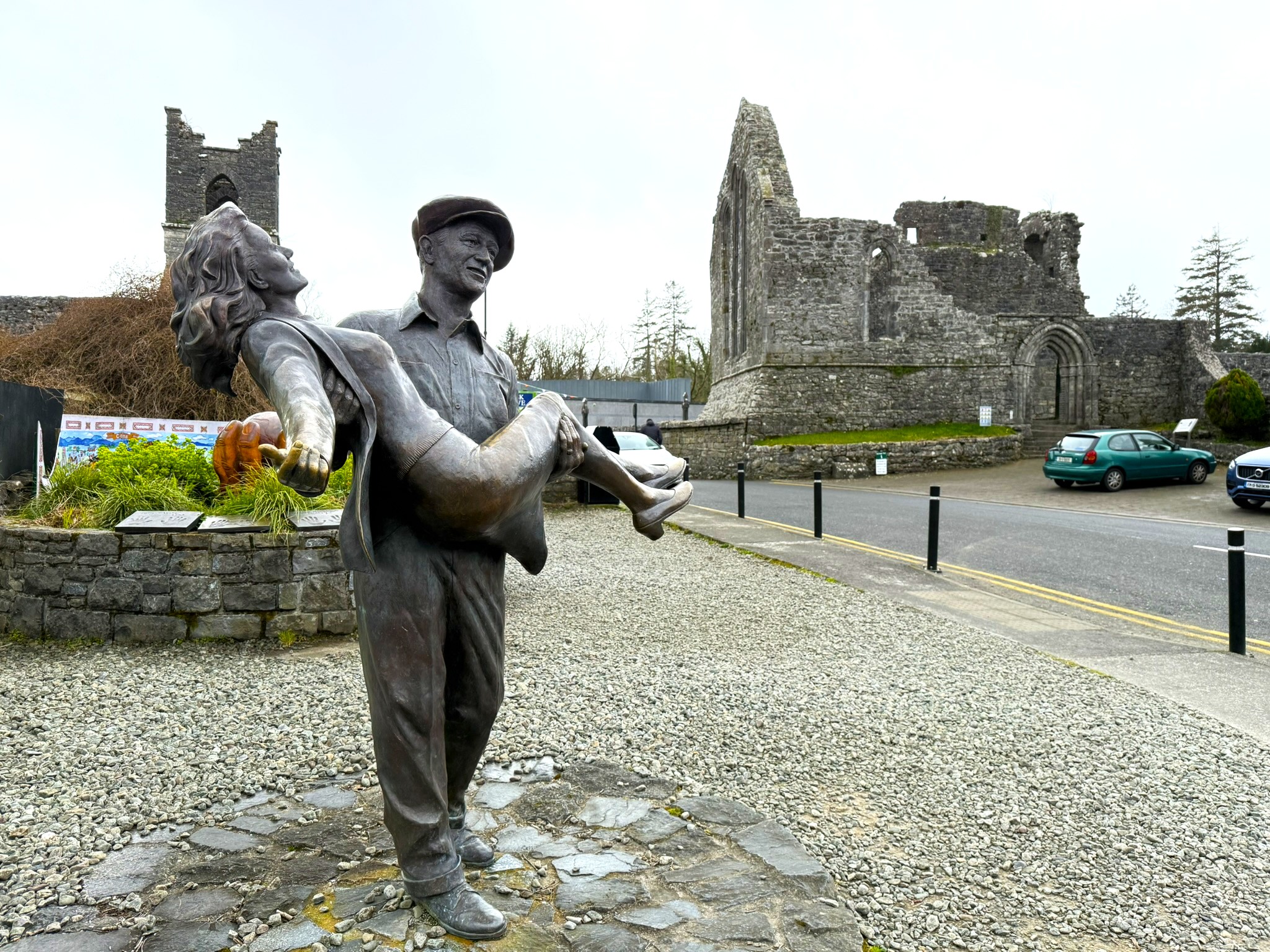 The Quiet Man statue in Cong with Cong Abbey behind