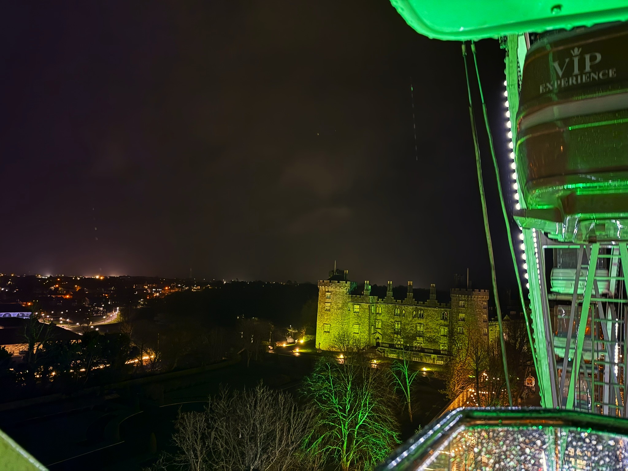 Kilkenny Castle lit green at night, seen from the top of the Ferris wheel