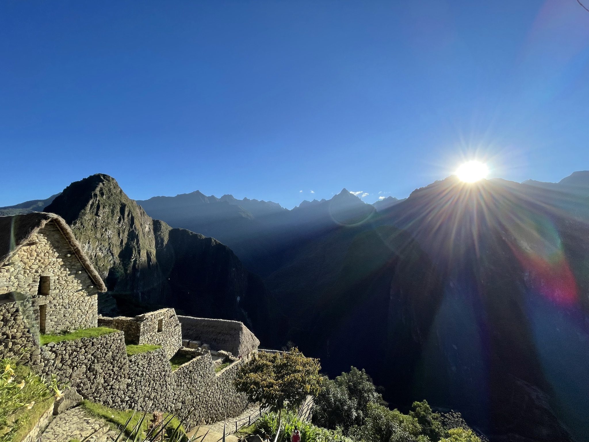 Machu Picchu at sunrise — sun flare across the ancient citadel